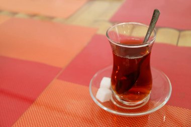 Lale şeklinde bardakta sıcak Türk çayı ve renkli öğle yemeği maketlerine ayrılmış şeker küpleri.