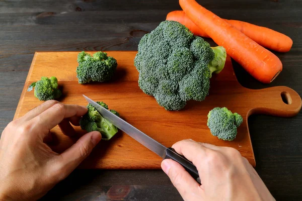 Hand Cutting Raw Brokoli Wooden Chopping Board Blurry Carrots Backdrop — Stok Foto