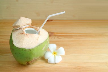 Hindistancevizi kabuğundan taze hindistan cevizi suyu ve ahşap masaya izole edilmiş Plumeria çiçeği.