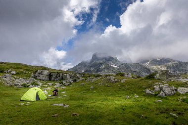 Bulgaristan 'daki Rila Dağı' nda yürüyüş yapan bir adam, dağda çadırının yanında oturuyor..
