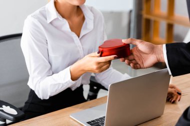 Ofisteki kadına hediye kutusu veren işadamı manzarası.