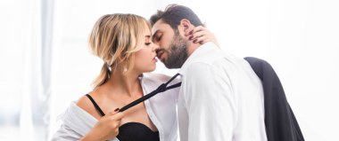 Ofiste flört ederken iş adamı kravatını çeken seksi kadın, panoramik çekim.