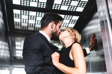 Businessman kissing colleague in office elevator clipart