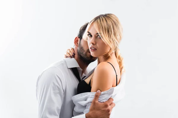 Seksi iş kadını kameraya bakıyor ve ofiste iş arkadaşına sarılıyor.