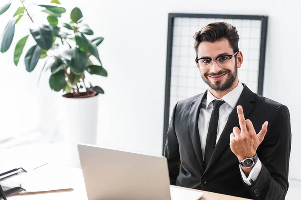 Hombre Negocios Sonriente Mostrando Gesto Dedo Medio Mesa Oficina — Foto de Stock