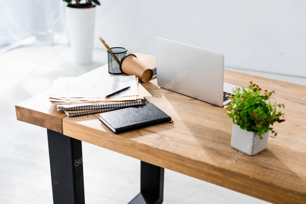 Workplace with laptop, stationery and coffee to go