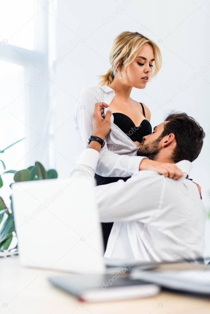 Businessman taking off shirt of sexy woman in office