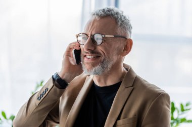 Mutlu ve sakallı iş adamı akıllı telefondan konuşuyor. 