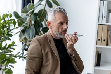 İşadamı ofisteki yeşil santrallerin yakınında sesli mesaj kaydediyor 
