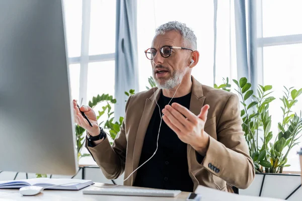 Hombre Negocios Auriculares Hablando Cerca Del Monitor Computadora Gesticulando Mientras — Foto de Stock