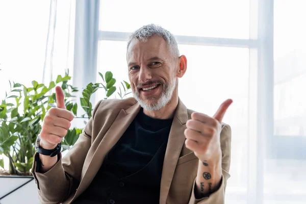 Happy Tattooed Businessman Showing Thumbs While Looking Camera — Stock Photo, Image