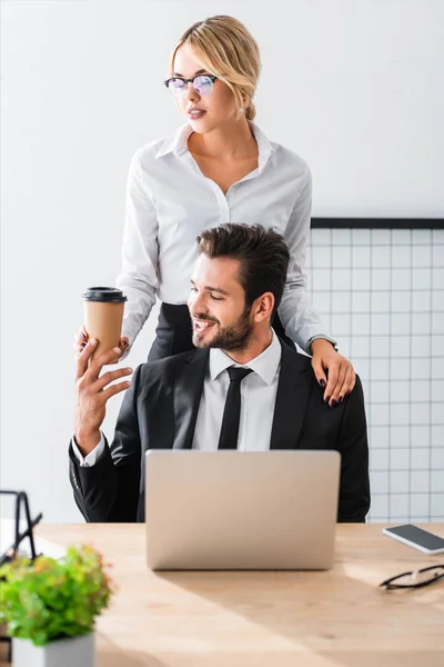 Attractive secretary giving coffee to smiling businessman — Stock Photo