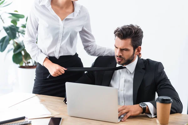 Empresaria tirando hombre de negocios empate en el lugar de trabajo - foto de stock