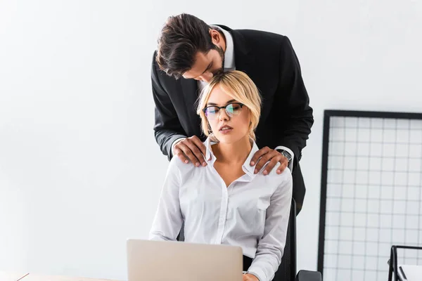 Businessman kissing colleague with laptop in office — Stock Photo