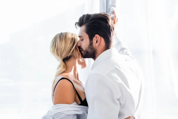 Businessman kissing sexy colleague near office window — Stock Photo