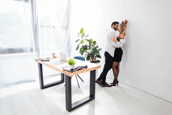 Side view of business couple kissing by wall in office — Stock Photo