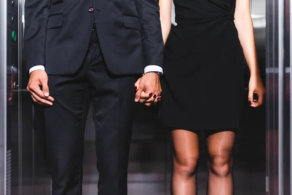 Vista recortada de pareja de negocios tomados de la mano en el ascensor de oficina - foto de stock