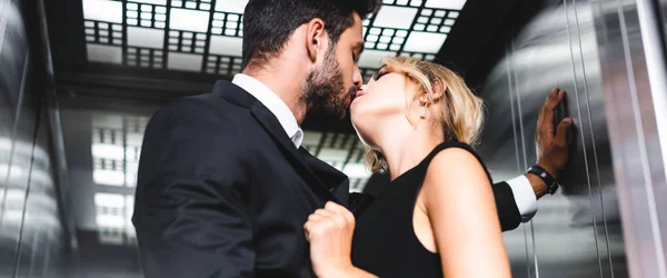 Panoramic shot of businessman kissing woman in office elevator — Stock Photo