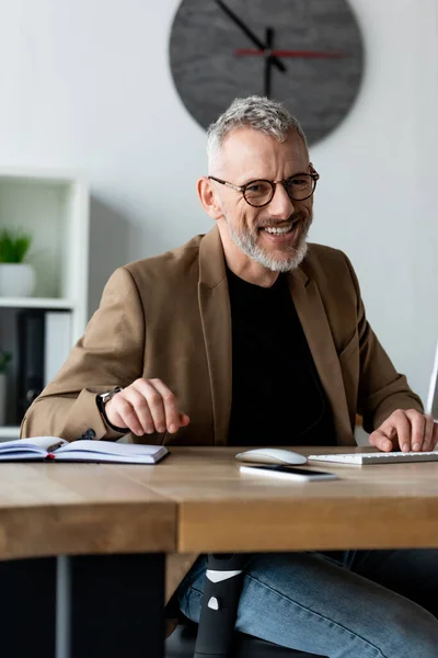 Избирательный фокус жизнерадостного бизнесмена в очках, улыбающегося в офисе — стоковое фото