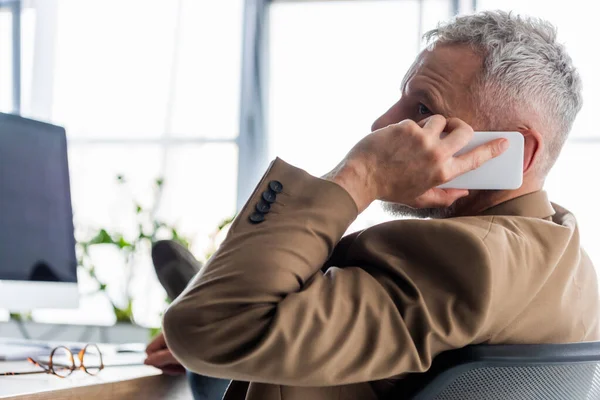 Selective focus of businessman covering face while talking on smartphone — Stock Photo