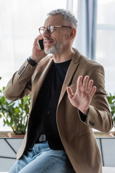 Selective focus of bearded businessman in glasses gesturing and talking on smartphone — Stock Photo