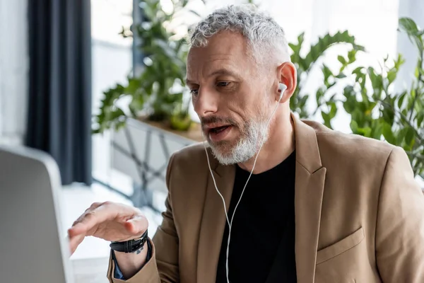 Selective focus of businessman in earphones gesturing in office — Stock Photo