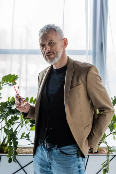 Gutaussehender und bärtiger Geschäftsmann blickt im Büro in die Kamera — Stockfoto