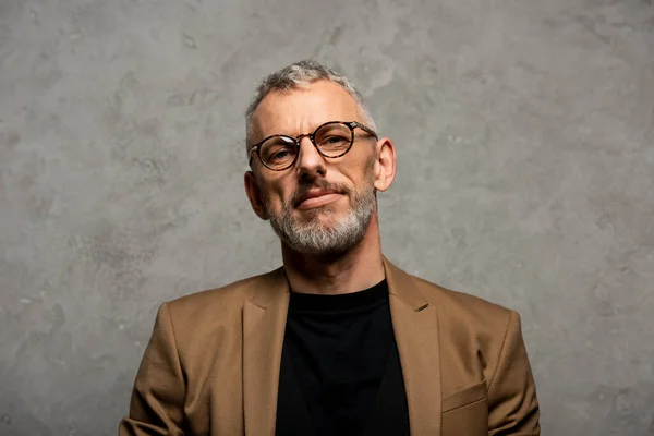 Schöner Geschäftsmann mit Brille blickt in die Kamera auf grau — Stockfoto