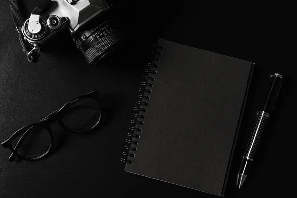 Câmera retro com notebook preto em fundo preto e copiar sp — Fotografia de Stock