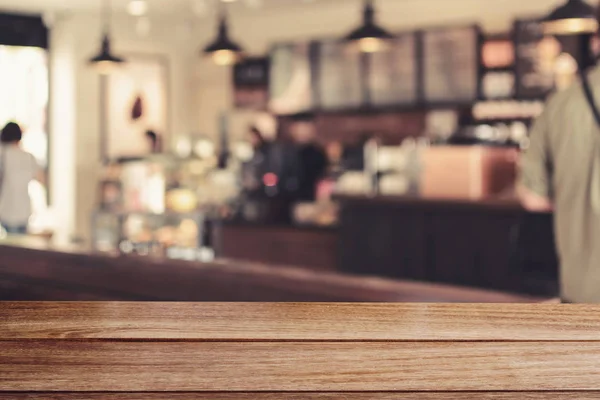 Houten tafelblad met beeld wazig bar in coffeeshop — Stockfoto