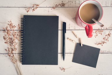 Boş defter ile kırmızı fincan kahve ve kurutulmuş çiçek