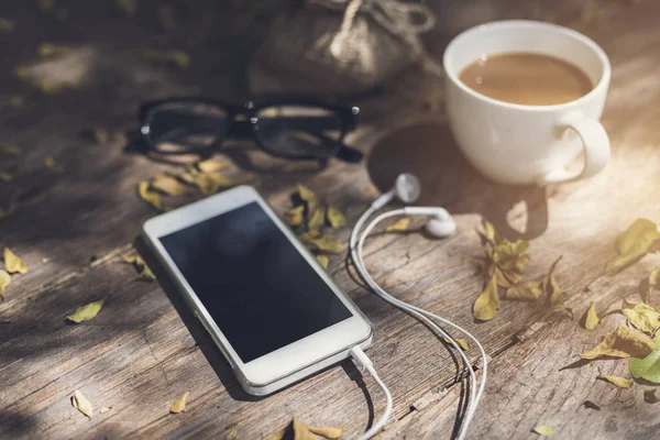 Tasse de café et téléphone portable sur table en bois dans le jardin — Photo