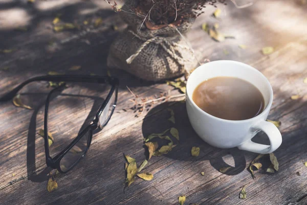 Glasögon med kopp kaffe på träbord — Stockfoto