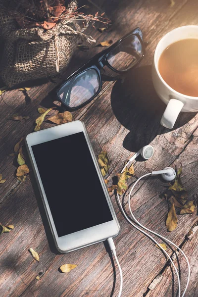 Mobiltelefon med kopp kaffe på träbord — Stockfoto