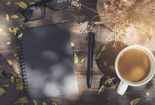 Anteckningsbok med kopp kaffe på träbord — Stockfoto