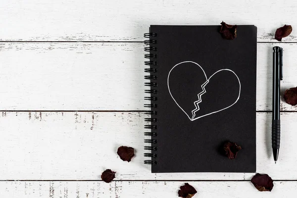 Rotes gebrochenes Herz mit getrocknetem Rosenblatt und Notizbuch — Stockfoto