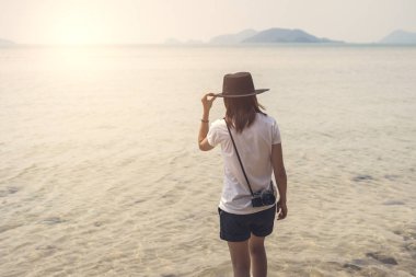 Genç bir kadın yolcu ile sahilde retro fotoğraf makinesi
