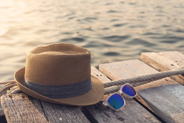 Hut und Sonnenbrille auf Holzbrücke — Stockfoto