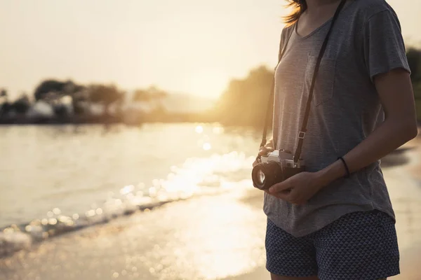 Young woman traveller with retro camera on the beach — Stock Photo, Image