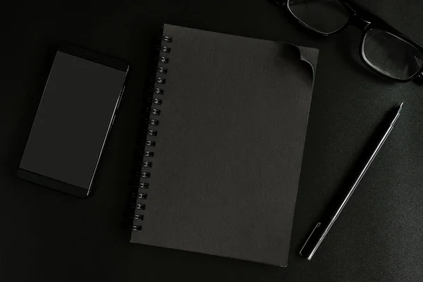 Notebook preto e celular no escritório de mesa — Fotografia de Stock