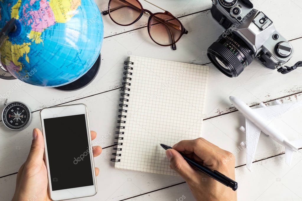Traveler planning trip on notebook and smart phone
