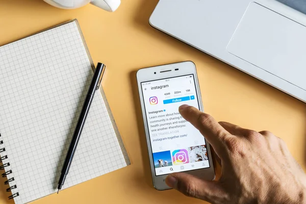 Bir adam akıllı telefon Instagram uygulama ile ekranda tutar.