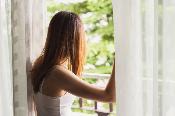 Ung asiatisk kvinna öppna gardiner på morgonen — Stockfoto