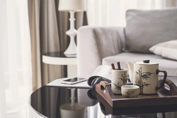 Cup of tea on wooden tray on a round table with sofa in living r — Stock Photo, Image