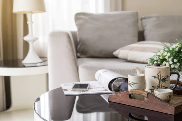 Cup of tea on wooden tray on a round table with sofa in living r — Stock Photo, Image