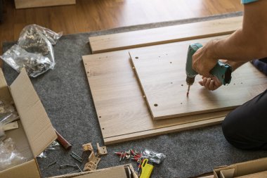 işçi mobilya yüklemek için elektrikli tornavida kullanın