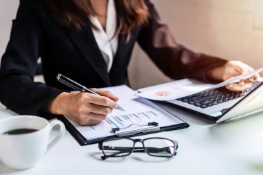 Masa başında bilgisayar ve pazarlama grafikleri istatistik analiziyle çalışan iş kadını