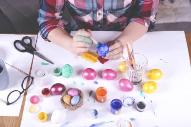 Paskalya yumurtalarını boyayan kadın eller. Renkli paskalya yumurtaları