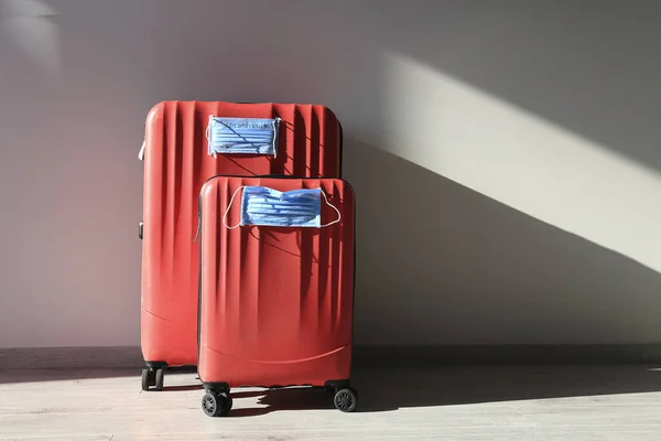 Two red luggages with protective masks to protect against coronavirus, global epidemic concept. Cancelled flights. Stop Travel.