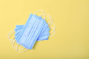 Gribe karşı korunmak için tıbbi maskeler ve sarı arka planda koronavirüs. Cerrahi koruyucu maske. Virüsün yayılmasını önlemek ve salgın COVID-19.